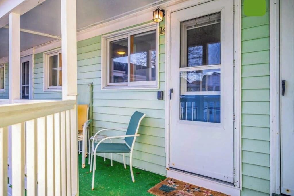 A porch with a white railing, a green chair, and a door with a window.