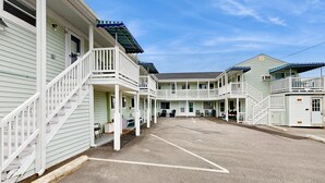 Ein Motel mit mehreren Balkonen, einem überdachten Parkplatz und blauem Himmel.
