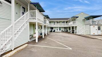 A motel with multiple balconies, a covered parking area, and a clear sky.