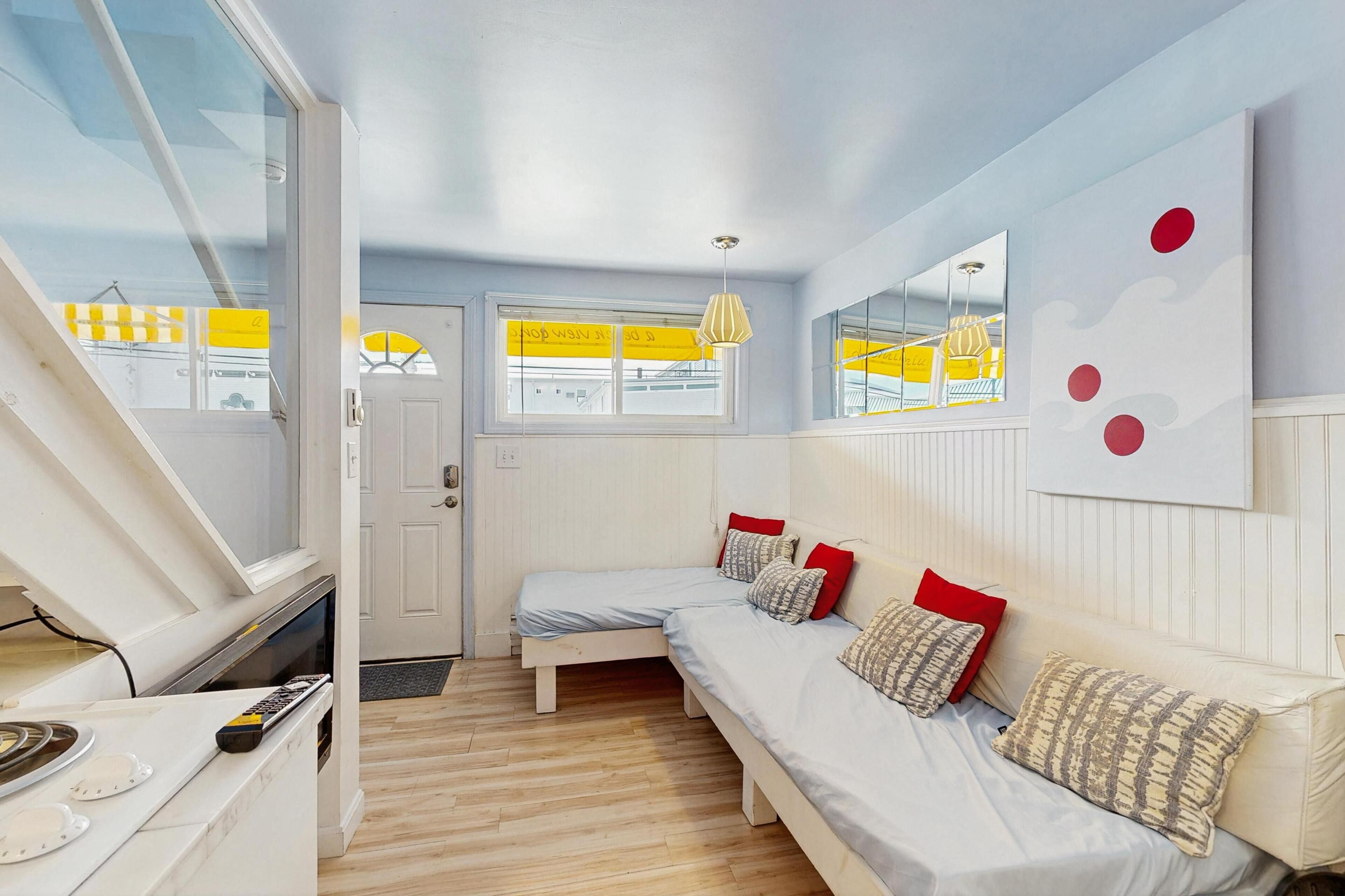 A room with a bed, a window, a door, and a view of the outside.