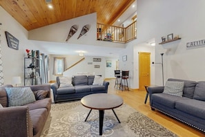 A spacious living area with a high ceiling, a balcony, and a dining area. - Two-level Townhome with Gas Fireplace, Deck, and Grill - Amazing Location (Bartlett)