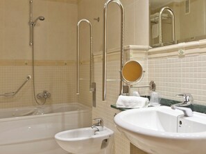 A bathroom with a bathtub, two sinks, a mirror, and grab bars. - Magic Balneario (Oropesa del Mar)