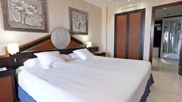 Una habitación de hotel con una cama grande, dos mesitas de noche, un cabecero de madera y obras de arte en las paredes.
