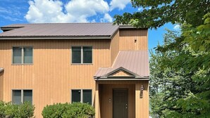 Un edificio di due piani con facciata marrone, un ingresso con porta e un piccolo portico.
