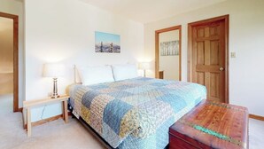 Una camera da letto con un letto, lampade sui comodini, un quadro appeso al muro e una porta in legno.