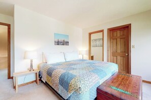 A bedroom with a bed, bedside lamps, a picture on the wall, and a wooden door. - Mountain-view condo with deck,  W/D - close to ski/hike/shopping (Bartlett)