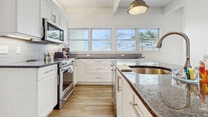 Eine moderne Küche mit weißen Schränken, einer Edelstahl-Spüle und einem großen Fenster für natürliches Licht.