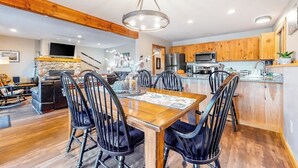 Een moderne keuken met houten kastjes, een centraal eiland en een eethoek met een houten tafel en stoelen.