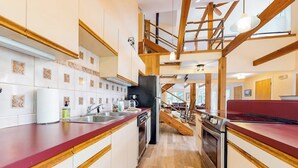 Una cucina moderna con travi in legno, un piano di lavoro rosso e un forno a incasso.