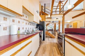 Une cuisine moderne avec des poutres en bois, un plan de travail rouge et un four encastré.