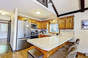 Eine Küche mit Holzausstattung, einem Edelstahlkühlschrank, einer Mikrowelle und einer großen Kochinsel mit Sitzgelegenheiten.