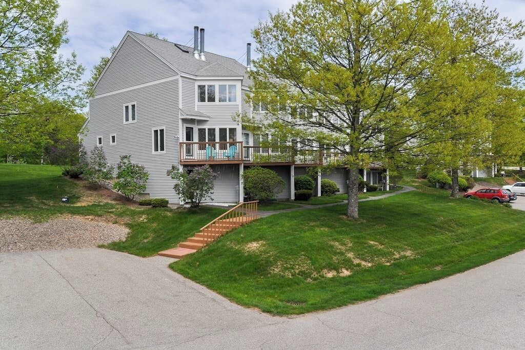 Une maison à deux étages avec un porche à l’avant, une terrasse couverte et un escalier menant à l’entrée.
