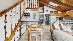 Ein großzügiges Loft mit einer Holztreppe, einem Essbereich, einer Couch und einer Küche.
