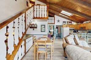 A spacious loft with a wooden staircase, a dining area, a sofa, and a kitchen. - Convenient Townhouse plus Loft w/Free WiFi, Full Kitchen, Gas Fireplace, & More (Bartlett)