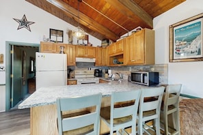 A kitchen with wooden cabinets, granite countertops, a built-in microwave, and a star decoration on the wall. - Convenient Townhouse plus Loft w/Free WiFi, Full Kitchen, Gas Fireplace, & More (Bartlett)
