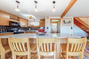 A kitchen with wooden cabinets, a large island with chairs, a microwave, and a stove. - Charming retreat + loft w/deck, gas grill, private washer/dryer, and jetted tub (Bartlett)