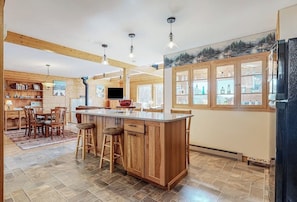 A spacious kitchen with a central island, wooden cabinetry, and a large window. - Charming retreat + loft w/deck, gas grill, private washer/dryer, and jetted tub (Bartlett)