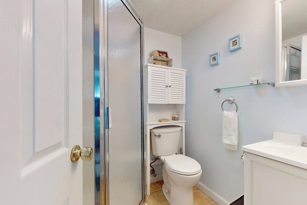 Une salle de bain équipée de toilettes, d’un lavabo, d’un miroir et d’un meuble de rangement.