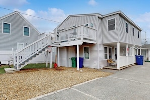 A two-story building with a balcony, a staircase, and a covered porch area. - Cute getaway near the beach with full kitchen, fast WiFi, & furnished deck (Hampton)
