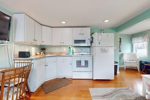 A compact kitchen with white cabinets, a microwave, an oven, and a refrigerator. - Cute getaway near the beach with full kitchen, fast WiFi, & furnished deck (Hampton)