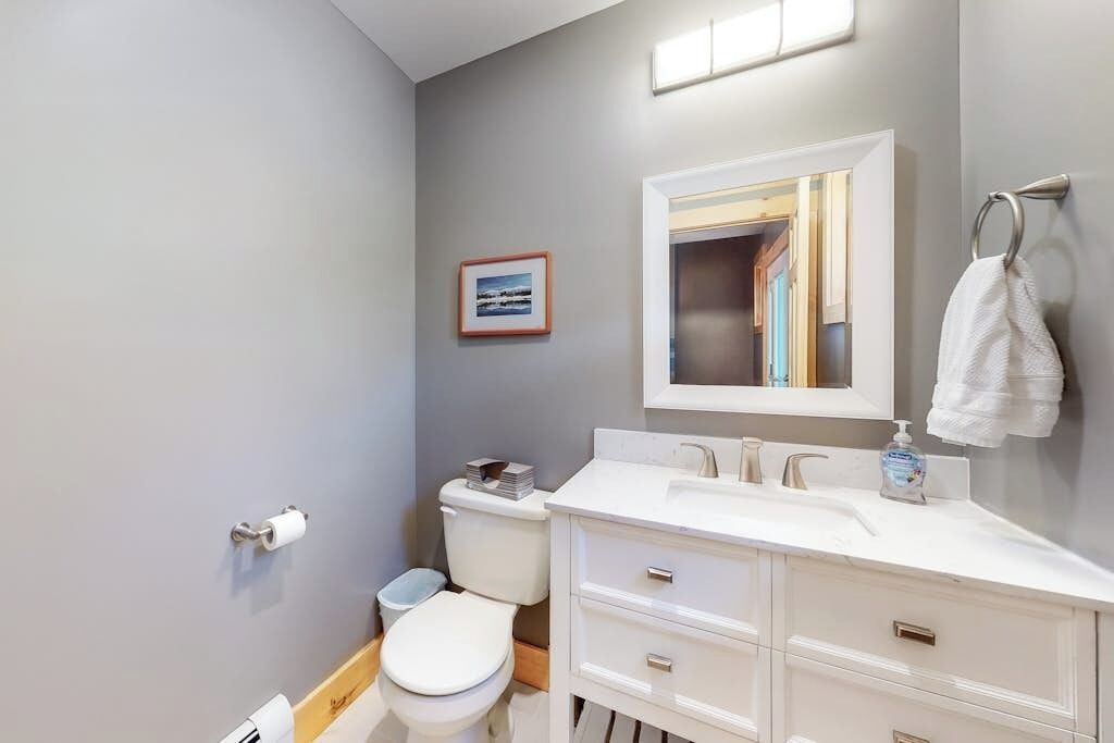 A bathroom with a toilet, sink, mirror, and towel rack.