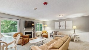A living room with a sofa, chairs, a coffee table, a fireplace, and a TV.