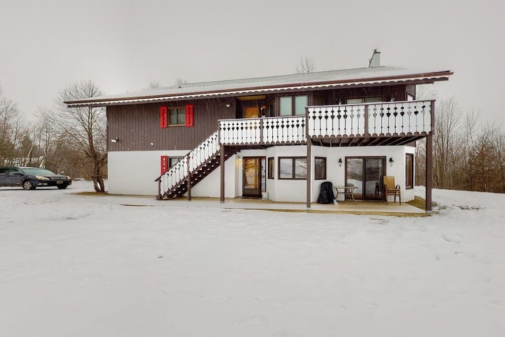 En tvåvåningsbyggnad med en balkong, en trappa och ett takförsett utomhusområde med sittplatser.