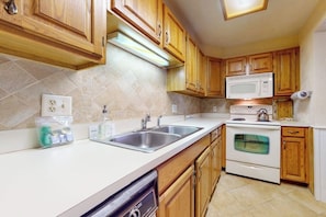 A kitchen with wooden cabinets, a microwave, an oven, a dishwasher, and a tiled backsplash. - Dog-friendly condo near skiing with amazing Mt.Washington views, fireplace & W/D (Bartlett)