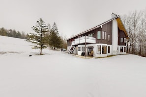 A two-story house with a balcony, a staircase, and a snow-covered landscape. - Dog-friendly condo near skiing with amazing Mt.Washington views, fireplace & W/D (Bartlett)