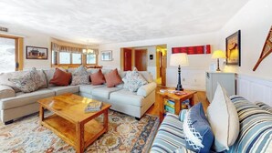 Un salon avec un canapé, une table basse, un divan à rayures et une lampe.