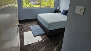A bedroom with a bed, a ceiling fan, a window, and a door. - Villa Malicamich - Tropical Escape (Puntarenas Province)