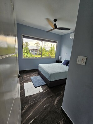 Ein Schlafzimmer mit Bett, Deckenventilator, Fenster und Tür.