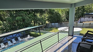 A balcony with a view of a swimming pool, lounge chairs, and a tiled floor. - Villa Malicamich - Tropical Escape (Puntarenas Province)