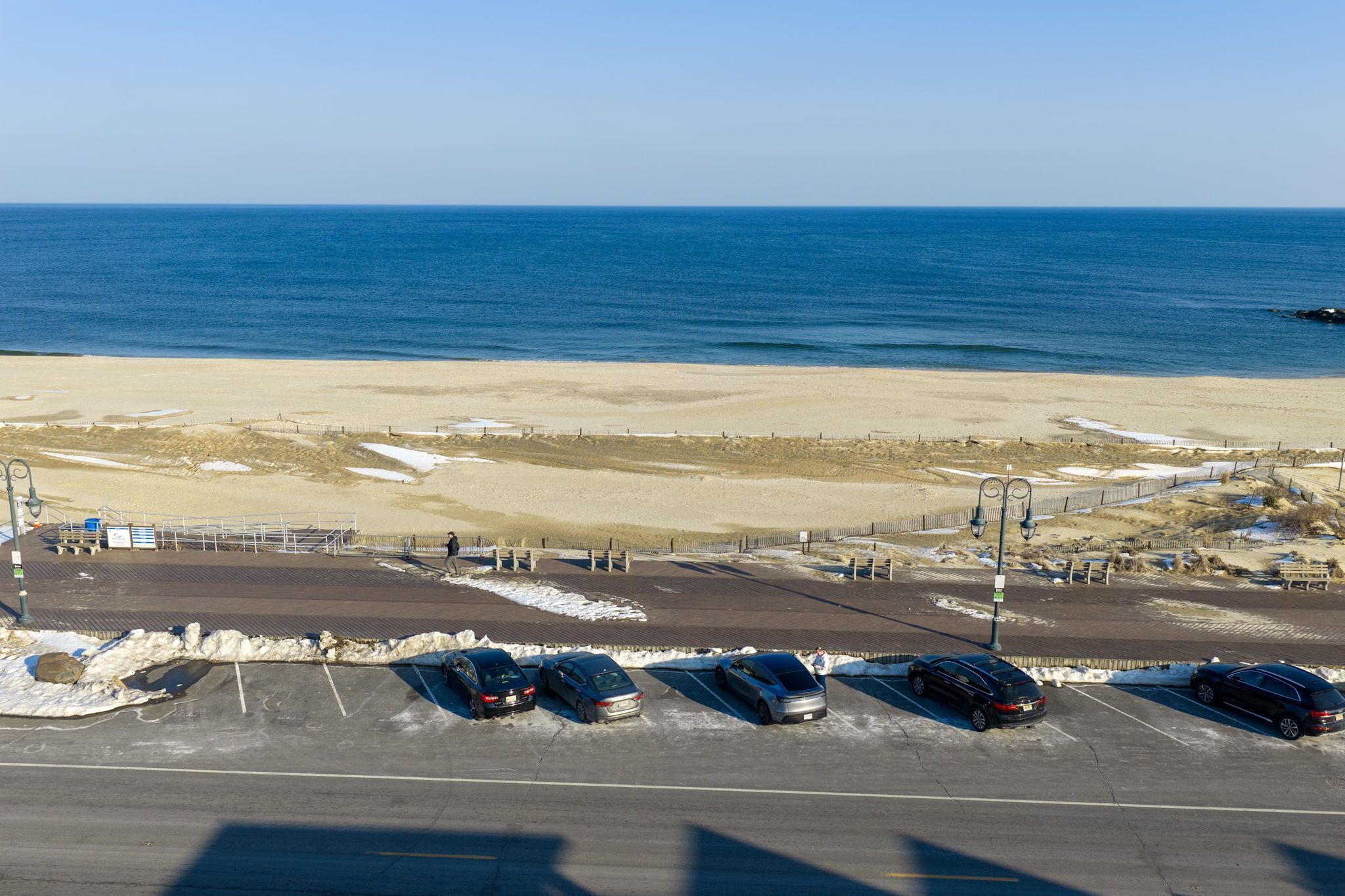 Un estacionamiento con coches, una playa y el océano al fondo.