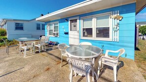 Une maison mobile bleue dotée d’un patio comprenant une table et des chaises.
