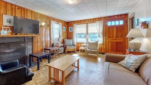 Un salon avec une cheminée, des murs en bois, un téléviseur et un canapé.