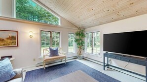 Ein geräumiges Wohnzimmer mit großem Fernseher, einer Bank und einer Topfpflanze.