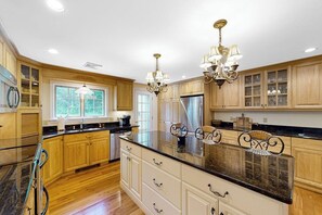 A spacious kitchen with wooden cabinets, a large island, and pendant lighting. - White Mountain Glen | House in Bartlett with hot tub, sauna, firepit & game room (Bartlett)