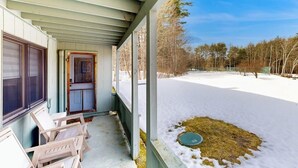 A covered porch with a view of a snowy yard and trees. - Snowbird-friendly home with heated pool, sauna, game room, tennis, BBQ, W/D (Bartlett)
