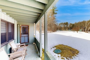 A covered porch with a view of a snowy yard and trees. - Snowbird-friendly home with heated pool, sauna, game room, tennis, BBQ, W/D (Bartlett)