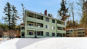 A multi-story building with balconies, surrounded by snow and trees. - Snowbird-friendly home with heated pool, sauna, game room, tennis, BBQ, W/D (Bartlett)
