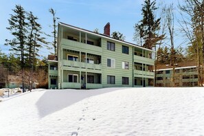 A multi-story building with balconies, surrounded by snow and trees. - Snowbird-friendly home with heated pool, sauna, game room, tennis, BBQ, W/D (Bartlett)