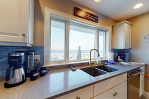 A kitchen with a coffee maker, two mugs, a sink, and a window with a view. - Oceanfront Stunner w/ Kayaks, Beach Gear, Fireplace, Amazing Water Views & Pond (Rye)