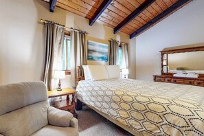 A hotel room with a bed, a chair, a desk, a lamp, and a painting on the wall. - Sweet condo with fast WiFi, gas fireplace, & W/D - close to slopes (Bartlett)