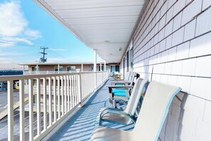 A balcony with a view of the street, a railing, and a row of chairs. - 2nd-floor studio 1 block from the beach with pool, beach access, grills, & W/D (Hampton)