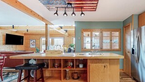 Una cocina moderna con armarios de madera, una isla central y un refrigerador de acero inoxidable.