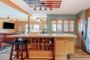 A modern kitchen with wooden cabinetry, a central island, and a stainless steel refrigerator. - Secluded mountain getaway with private sauna, large deck, sweeping views & WiFi (Bartlett)