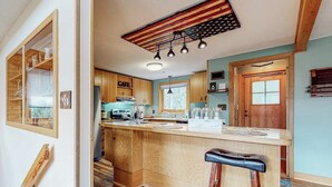 Una cocina con armarios de madera, una isla central, taburetes de bar y un techo con diseño de estrellas.