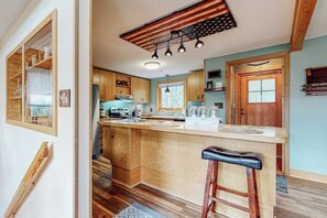 A kitchen with wooden cabinets, a central island, bar stools, and a ceiling with a star pattern. - Secluded mountain getaway with private sauna, large deck, sweeping views & WiFi (Bartlett)