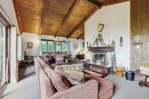 A cozy living room with a wooden ceiling, a fireplace, and a sofa with patterned cushions. - Dog-friendly home with stunning views & balcony, near Cannon Mountain (Franconia)